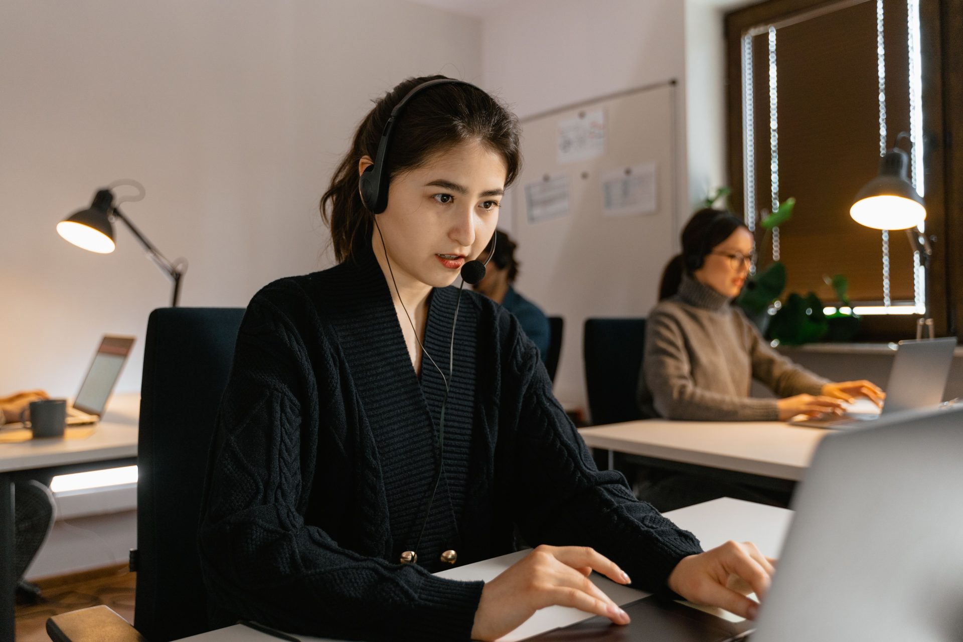 Konzentrierte Call-Center-Mitarbeiter arbeiten mit Headsets in einer modernen Büroumgebung.