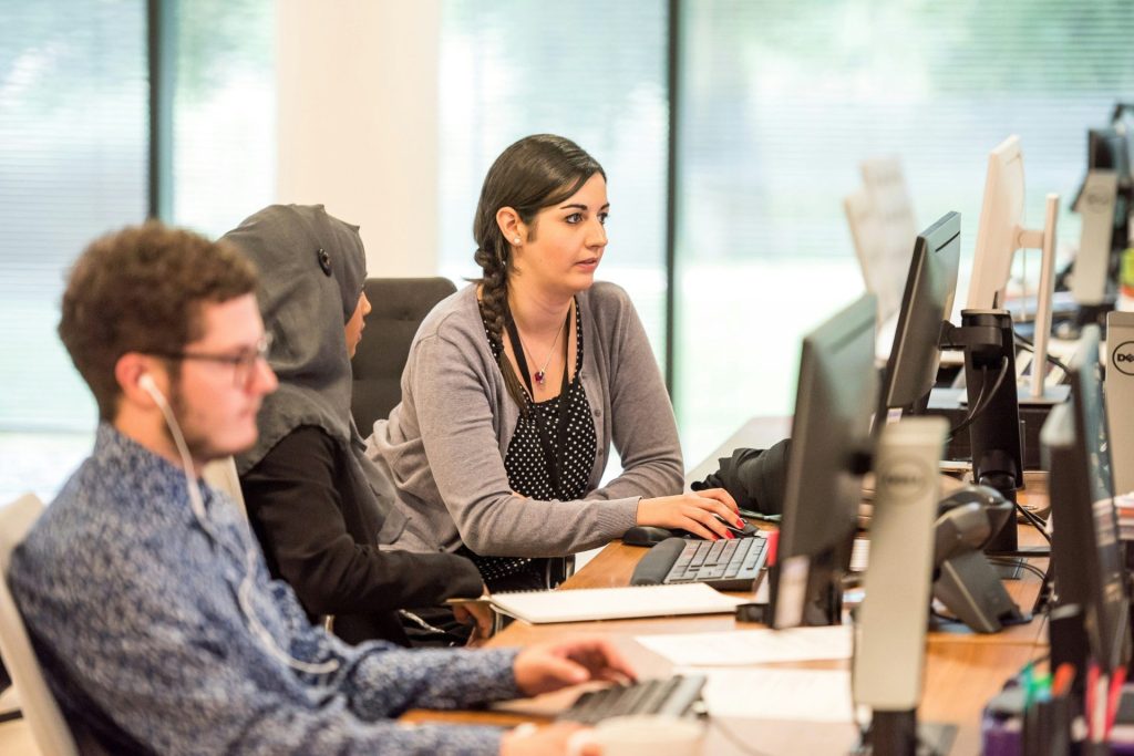 Unbekannte Personen, die drinnen einen Computer benutzen